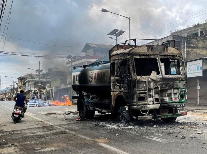 A scooterist rides past a damaged water tanker that was set afire during a protest by tribal groups in Churachandpur in the northeastern state of Manipur, India, May 4, 2023. REUTERS/Stringer/File Photo