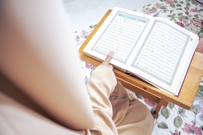 Muslim woman reading from the Quran. She was wearing a polite Abaya Muslim dress.