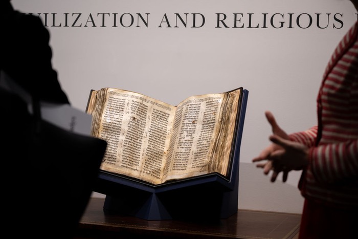 NEW YORK, NEW YORK - MAY 08: People view The Codex Sassoon while on display during a press preview at Sotheby's on May 08, 2023 in New York City. The codex is the oldest surviving Hebrew Bible or Tanakh as its used today in contrast to the dead sea scrolls which are older but the books are in separate scrolls. The Book is approximately 1000 years old and is estimated to be auctioned at 30-50 Million dollars and that would make it the most valuable historical document to appear in auction. (Photo by Alexi Rosenfeld/Getty Images)