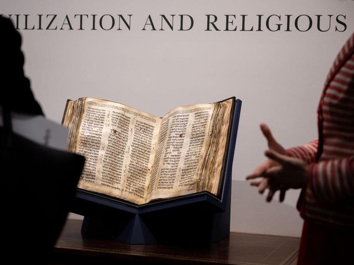 NEW YORK, NEW YORK - MAY 08: People view The Codex Sassoon while on display during a press preview at Sothebys on May 08, 2023 in New York City. The codex is the oldest surviving Hebrew Bible or Tanakh as its used today in contrast to the dead sea scrolls which are older but the books are in separate scrolls. The Book is approximately 1000 years old and is estimated to be auctioned at 30-50 Million dollars and that would make it the most valuable historical document to appear in auction. (Photo by Alexi Rosenfeld/Getty Images)