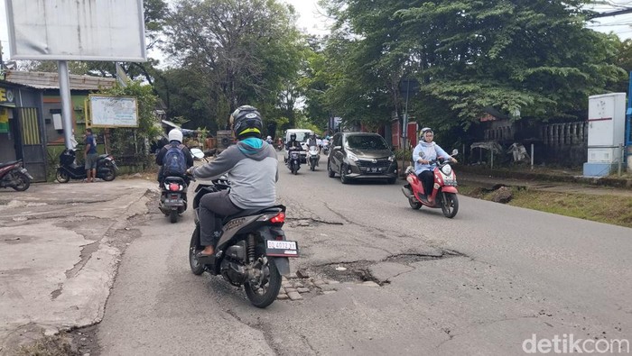 Pengendara motor menghindari lubang di Jalan Antang Raya Makassar.