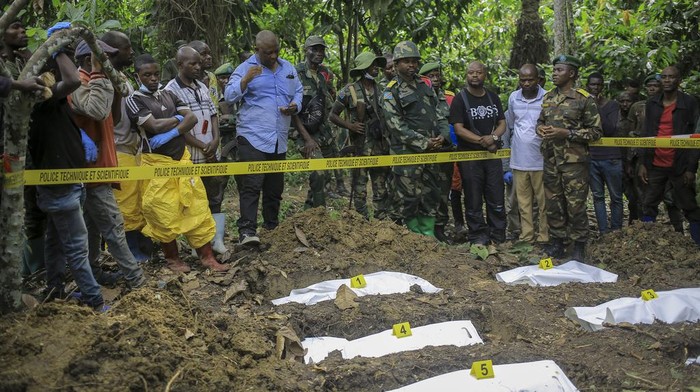 A man looks over the cordon at human remains in a mass grave in the village of Ndoma, near Beni in North Kivu, Congo Saturday, May 6, 2023. The remains of at least 20 people were found buried in a mass grave in an area used to cultivate cacao in Ndoma village in Congo's North Kivu province this weekend, according to local authorities and a military spokesperson. (AP Photo)