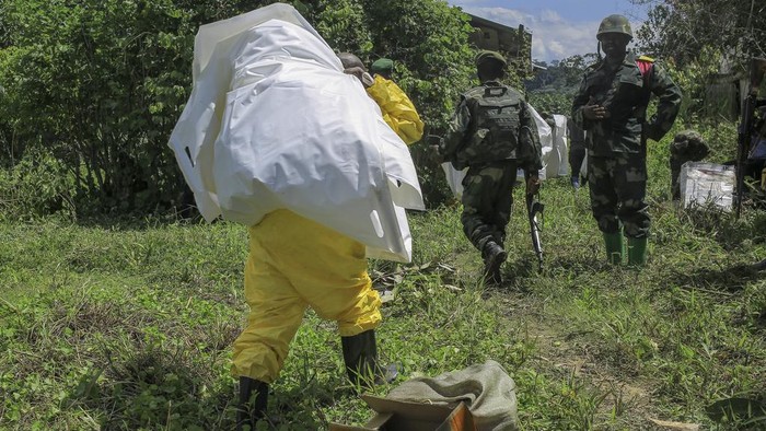 Potret Penemuan Kuburan Massal di Kongo A man looks over the cordon at human remains in a mass grave in the village of Ndoma, near Beni in North Kivu, Congo Saturday, May 6, 2023. The remains of at least 20 people were found buried in a mass grave in an area used to cultivate cacao in Ndoma village in Congo's North Kivu province this weekend, according to local authorities and a military spokesperson. (AP Photo)