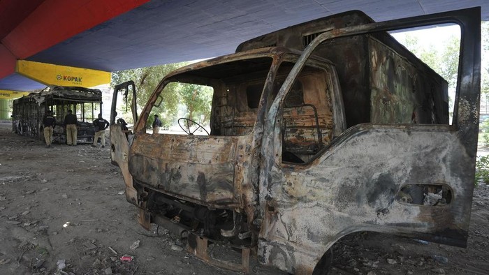 Police officers examine burnt vehicles under a bridge on a road, a day after violent protests of Pakistan's former Prime Minister's supporters following his arrest, in Karachi, Pakistan, Wednesday, May 10, 2023. Pakistan braced for more turmoil a day after former Prime Minister Khan was dragged from court in Islamabad and his supporters clashed with police across the country. The 71-year-old opposition leader is expected in court later Wednesday for a hearing on keeping Khan in custody. (AP Photo/Fareed Khan)