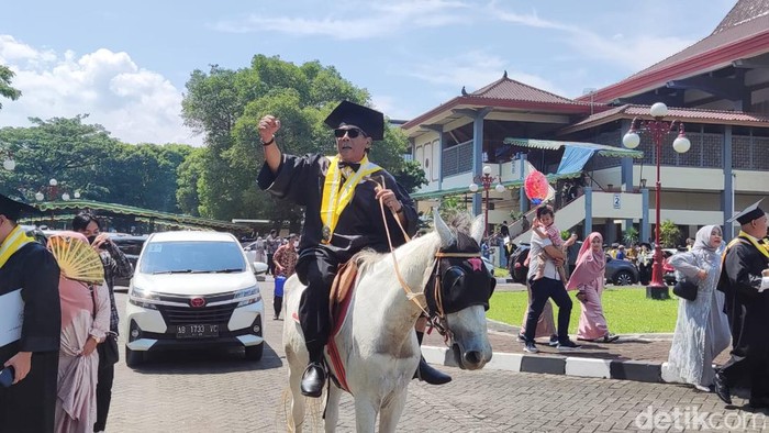 Momen Endra Harsaya, mahasiswa program pasca sarjana UGM menaiki kuda usai upacara wisuda, Rabu (10/5/2023).