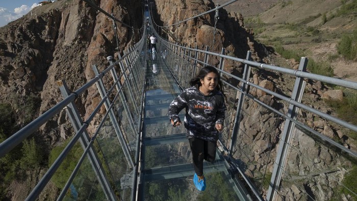 A young Iranian woman runs along a glass suspension bridge in the Heer recreation area near the city of Ardabil in Ardabil province, 617 km (383 miles) northwest of Tehran, April 27, 2023.  (Photo by Morteza Nikoubazl/NurPhoto via Getty Images)