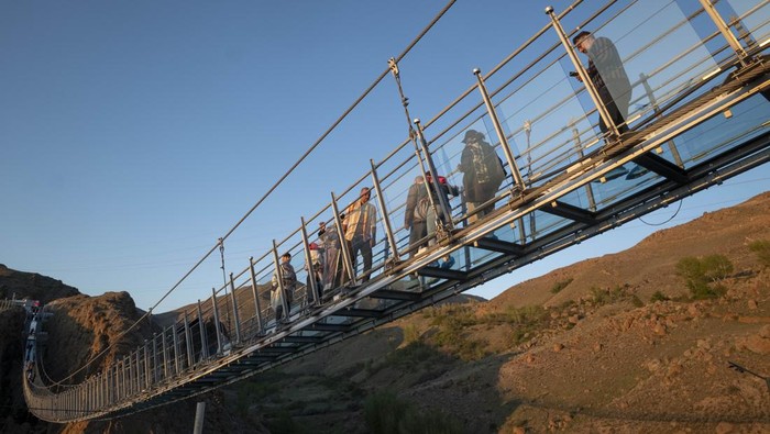 Iran Punya Jembatan Gantung Kaca Tertinggi di Timur Tengah, Berani Lewat? A young Iranian woman runs along a glass suspension bridge in the Heer recreation area near the city of Ardabil in Ardabil province, 617 km (383 miles) northwest of Tehran, April 27, 2023. (Photo by Morteza Nikoubazl/NurPhoto via Getty Images)