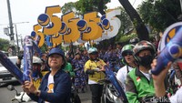 Rombongan tiba dengan iring-iringan ojek online dan marching band. Mereka juga tampak membawa bendera Partai NasDem, balon stik NasDem dan nomor urut 5.  