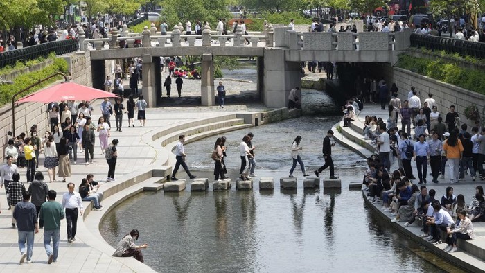 People walk along the public area of the Cheonggye Stream in Seoul, South Korea, Thursday, May 11, 2023. South Korea will drop its COVID-19 quarantine requirements and end testing recommendations for international arrivals starting next month after the World Health Organization declared the end of the global health emergency. (AP Photo/Ahn Young-joon)