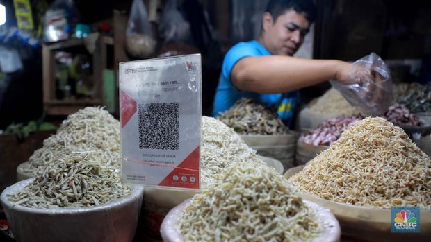 Seorang pedagang ikan asin menyiapkan dagangan dengan menyediakan sistem pembayaran Quick Response Code Indonesia Standard (QRIS) di Kawasan Pasar Tradisionan Pasar Minggu, Jakarta, Kamis, (11/5). (CNBC Indonesia/Muhammad Sabki)