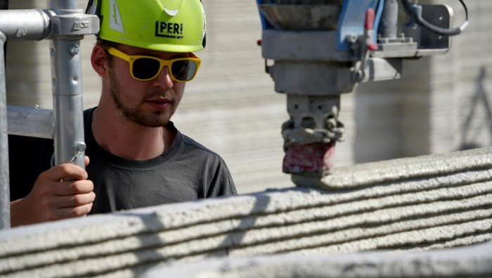Gokil! Jerman Bangun Gedung Pakai Mesin Cetak 3D A robot arm with the head of a 3D printer piles concrete layers to build what is described as “Europe’s largest 3D-printed building”, which is currently under construction and once built end of July it will house computer servers in Heidelberg, Germany, May 5, 2023. REUTERS/Max Schwarz