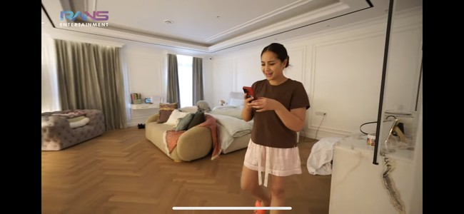 Untuk lantainya Raffi dan Nagita memilih vinyl model kayu yang membuat ruangan jadi terasa semakin nyaman. Di salah satu sisinya juga terdapat meja yang terbuat dari marmer, senada dengan yang terpasang di dinding belakang televisi. Foto: YouTube/Rans Entertainment
