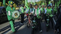 Mereka tampak menaiki sepeda. Selain itu, rombongan juga diiringi dengan marching band.   