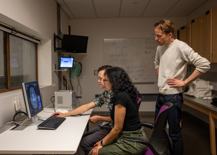 Tiga peneliti UT Austin Alex Huth (putih), Jerry Tang, dan Shailee Jain sedang mengumpulkan data aktivitas otak di  Biomedical Imaging Center at The University of Texas