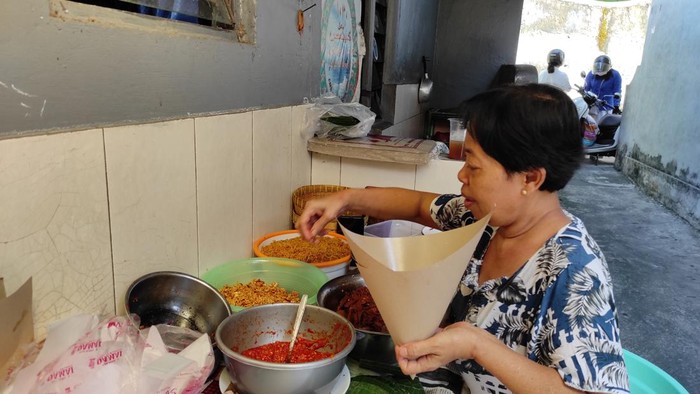 Ketut Ariani menjual nasi jinggo di sebuah gang di Jalan Diponegoro, Kota Denpasar, Sabtu (13/5/2023). (I Wayan Sui Suadnyana/detikBali)