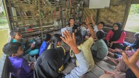 Salah seorang donatur (tengah belakang) mendongengkan cerita usai menyerahkan buku kepada anak-anak Taman Baco Atap Rumbe. 