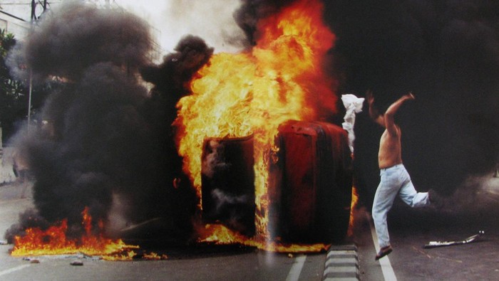FOTO ARSIP: Seorang pemuda melempar kainnya ke mobil yang terbakar di jalan Otista, Jakarta Timur, ketika massa tertahan di sekitar Jakarta, Kamis (14/5/1998). Kerusuhan massa telah terjadi setelah empat mahasiswa Universitas Trisakti ditembak mati oleh polisi anti huru hara sementara para mahasiswa mengadakan demonstrasi massa menyerukan agar Soeharto mengundurkan diri. FOTO ARSIP ANTARA FOTO/Zarqoni Maksum/asf/hp.