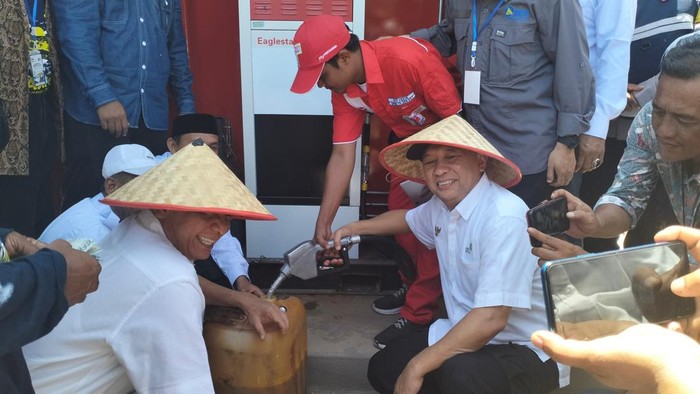 Menteri Koperasi dan UKM RI, Teten Masduki saat mengisi solar ke jeriken nelayan di Aceh Besar. (Agus Setyadi/detikSumut)