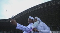 Sepasang suami istri foto selfie usai pelaksanaan nikah massal.  