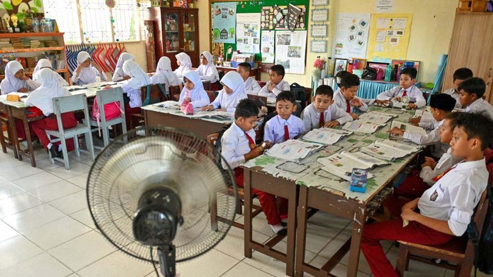 Cuaca Panas Melanda, Kipas Portabel Siaga A primary school student uses a portable fan to keep cool during hot weather in Banda Aceh on May 15, 2023. (Photo by CHAIDEER MAHYUDDIN / AFP) (Photo by CHAIDEER MAHYUDDIN/AFP via Getty Images)