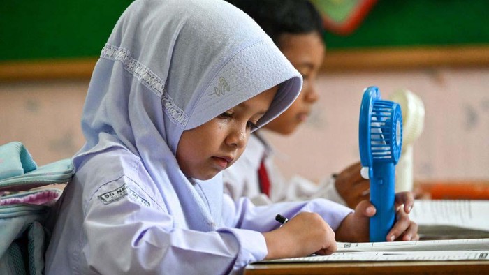 A primary school student uses a portable fan to keep cool during hot weather in Banda Aceh on May 15, 2023. (Photo by CHAIDEER MAHYUDDIN / AFP) (Photo by CHAIDEER MAHYUDDIN/AFP via Getty Images)