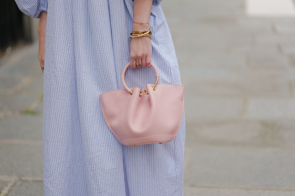 PARIS, FRANCE - APRIL 21: Alba Garavito Torre wears a baby blue and white striped print pattern puffy short sleeves / long dress from The Label Edition, gold bracelets, gold rings, a pale pink matte leather Capazo handbag from Saonara, during a street style fashion photo session, on April 21, 2023 in Paris, France. (Photo by Edward Berthelot/Getty Images)