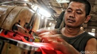 Seorang pekerja tengah menjahit bendera.