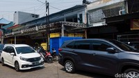 Petugas parkir sedang mengatur kendaraan. Keberadaan ruko yang memakan badan jalan dan menutup saluran air dapat mengakibatkan banjir.