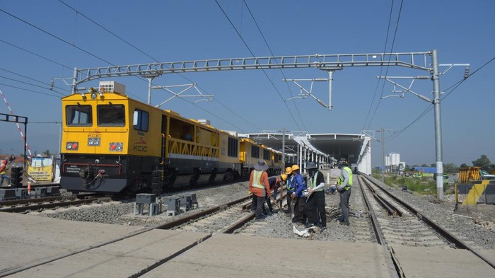 A train passes by workers checking an electronic system at the Tegalluar station of the China-made high speed railway connecting the capital city of Jakarta with Bandung, in Bandung, West Java on May 15, 2023. (Photo by TIMUR MATAHARI / AFP) (Photo by TIMUR MATAHARI/AFP via Getty Images)