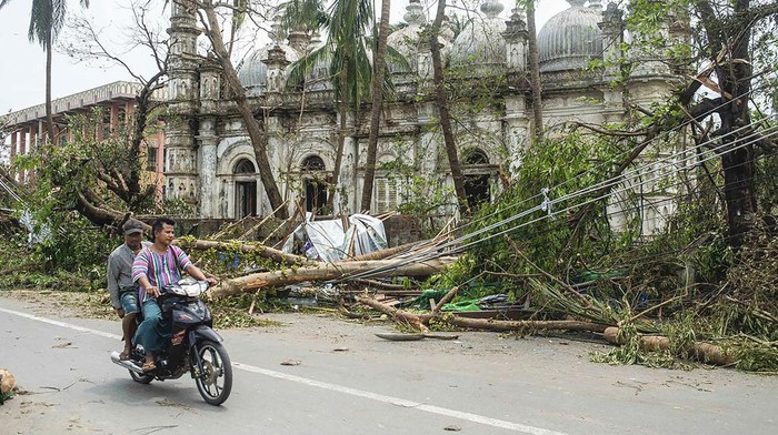 Locals ride motorbike on a road while fallen trees lie near a mosque after Cyclone Mocha in Sittwe township, Rakhine State, Myanmar, Monday, May 15, 2023. Rescuers on Monday evacuated about 1,000 people trapped by seawater 3.6 meters (12 feet) deep along western Myanmars coast after the powerful cyclone injured hundreds and cut off communications. (AP Photo)