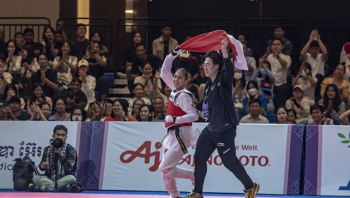 Atlet Taekwondo Indonesia Megawati Tamesti Maheswari (kiri) membawa bendera merah putih bersama pelatih Taekwondo Indonesia Kim Seung-ill (kanan) usai menang melawan atlet Taekwondo Thailand Chutikan Jongkolrattanawattana pada pertandingan taekwondo ‘under’ 53 kilogram putri SEA Games 2023, di Chory Changvar International Convention and Exibhition Center, Phnom Penh, Kamboja, Senin (15/5/2023). Megawati Tamesti Maheswari berhasil meraih medali emas usai mengalahkan atlet taekwondo Thailand dengan skor 2-1, sementara medali perak diraih atlet taekwondo Thailand Chutikan Jongkolrattanawattana serta medali perunggu diraih atlet taekwondo Filipina Baby Jessica Canabal dan atlet taekwondo Kamboja Mam Julie. ANTARA FOTO/Muhammad Adimaja/hp.