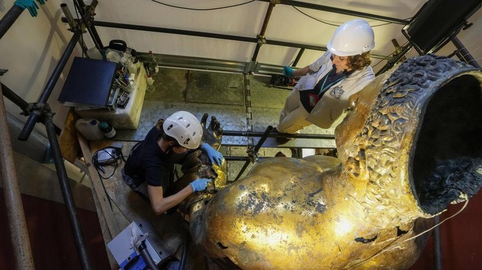Vatican Museum restorers Chiara Omodei Zorini, left, and Alice Baltera work on the bronze Hercules statue, in the Round Hall of the Vatican Museums, Thursday, May 11, 2023. Work will continue until December to reveal the 4-meter- (13-foot-) tall Hercules, believed to have stood in ancient Rome’s Pompey Theater, to its original golden sheen. The discovery of the gilded bronze in 1864 during work on a banker’s villa near Piazza dei Fiori made global headlines. (AP Photo/Andrew Medichini)