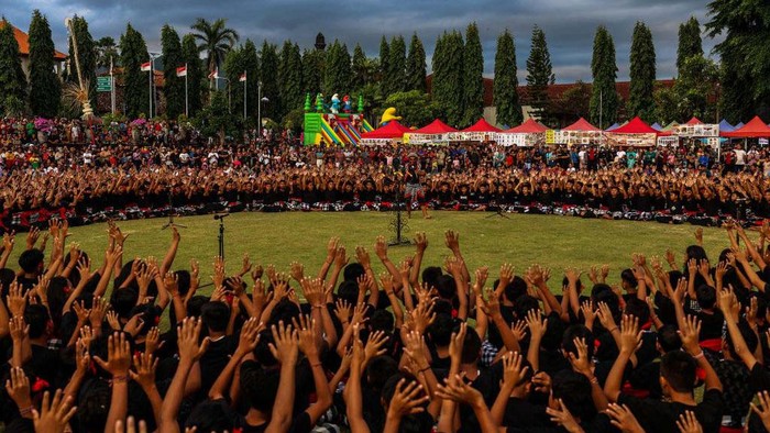 1.000 Pelajar Pentaskan Tari Kecak Kolosal di Bali Balinese students dancers raise their arms and chant in a frenzied chorus during the National Education Day in Klungkung, Bali, Indonesia, May 16, 2023. About 1,000 students danced on the field in a colossal show, and their chants of ''cak-cak'' took the place of musical instruments during the performance. The Kecak is an epic tale from the Ramayana, a Hindu holy book, that dramatizes the eternal conflict between good and evil. (Photo by Garry Lotulung/NurPhoto via Getty Images)