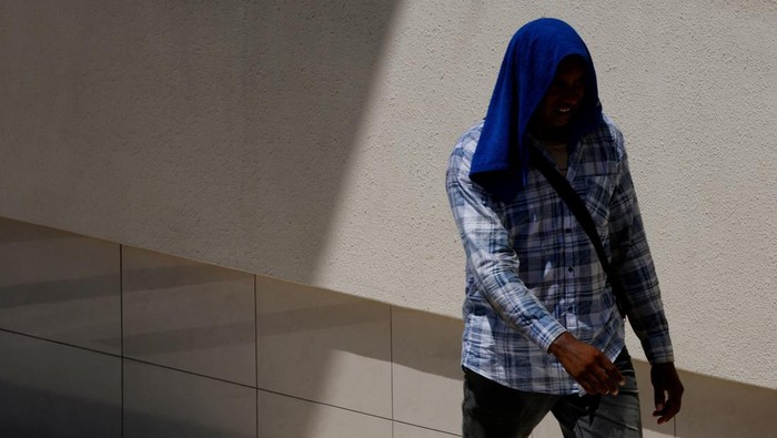 People shield themselves from the sun with umbrellas as they cross a street on a warm day in Singapore May 15, 2023. REUTERS/Edgar Su