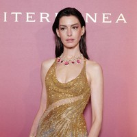 Anne Hathaway memadukan gaun dengan platform heels, perhiasan gelang di kedua tangan dan clutch mungil. Foto: Getty Images