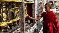 Seorang biksu muda tengah memutar roda doa.  