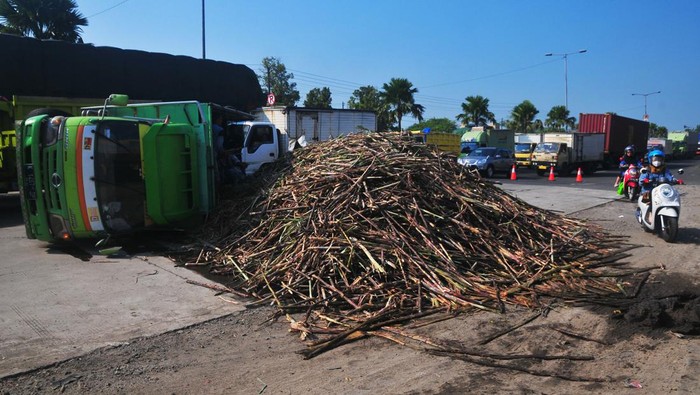 Pengendara sepeda motor melintas di samping truk yang mengalami kecelakaan tunggal di jalan pantura lingkar selatan Desa Ngembal Kulon, Kudus, Jawa Tengah, Rabu (17/5/2023). Mobil truk bernopol K 1467 SP mengangkut Tebu dari arah Sragen menuju Pati itu terguling akibat As roda patah sehingga menyebabkan sedikit ketersendatan arus lalu-lintas. ANTARA/Yusuf Nugroho/foc.
