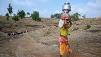 Seorang wanita membawa kendi berisi air yang dia kumpulkan dari sumur kering, di desa Koli, negara bagian Maharashtra, India barat, Senin (16/5/2023).  