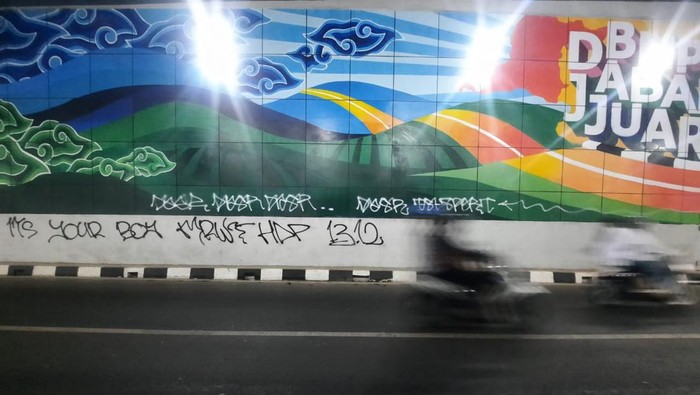 Coretan warna putih di tembok Underpass Dewi Sartika, Depok, belum juga dibersihkan oleh petugas. Malah muncul coretan baru warna hitam tepatnya di bawah gambar resmi yang dibuat Pemkot Depok.