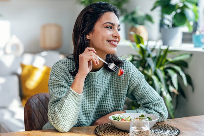 Ilustrasi wanita makan stroberi atau salad
