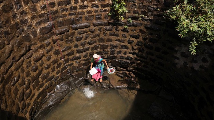Musim Panas Bikin India Krisis Air Parah Women gather around a well to draw water from it in Telamwadi, near Mumbai, India, May 16, 2023. REUTERS/Francis Mascarenhas