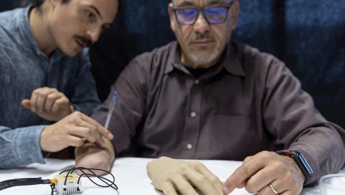 Fabrizio Fidati, who lost his right hand in an accident 25 years ago, points on a rubber hand where he feels on his fantom hand the pen that Francesco Iberite, neural engineer at the Scuola Superiore Sant'Anna (SSSA), applies on his limb during the presentation of bionic technology that helps amputees feel the temperature of objects again in their phantom hands at the Campus Biotech at the Swiss Federal Institute of Technology (EPFL) in Geneva, Switzerland April 19 , 2023. REUTERS/Denis Balibouse