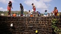 Sejumlah perempuan menurunkan wadah plastik yang diikatkan pada tali untuk menimba air dari sebuah sumur di Telamwadi, Mumbai, India, Selasa (16/5/2023).