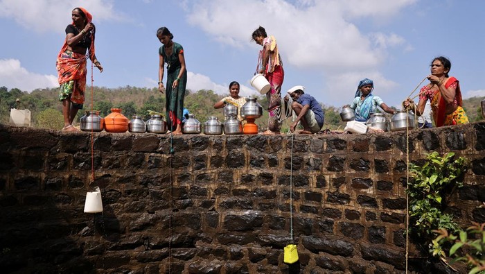 Women lower plastic containers attached to a rope to draw water from a well in Telamwadi, near Mumbai, India, May 16, 2023. REUTERS/Francis Mascarenhas      TPX IMAGES OF THE DAY