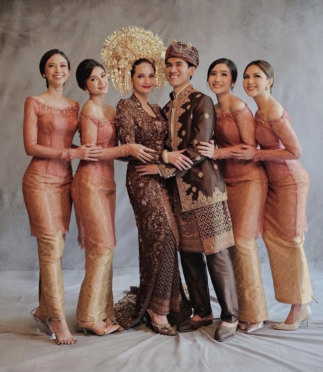 Senada dengan pernikahan Enzy yang mengusung adat Minang, kebaya bernuansa merah salmon itu dikombinasikan dengan songket emas yang menciptakan kesan mewah. (Foto: Instagram)