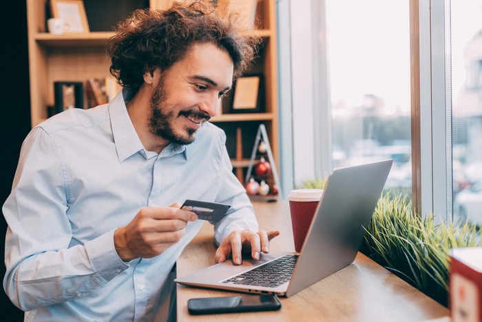 Man making an online payment via credit card on a laptop at an internet cafe.