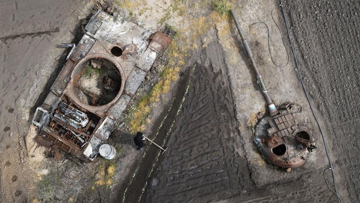 Tank-tank yang rusak akibat perang teronggok di perkebunan Desa Velyka Dymerka, Kyiv, Ukraina. Warga pun berkebun di antara tank-tank yang rusak.