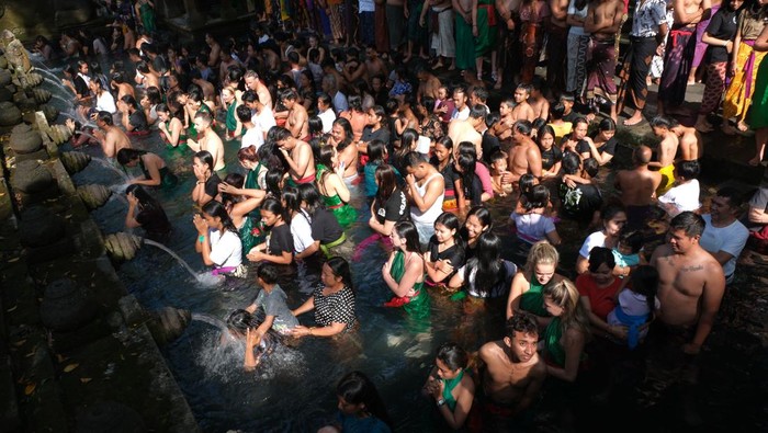 Wisatawan mancanegara berbaur dengan umat Hindu yang melakukan ritual melukat atau pembersihan diri pada hari Banyu Pinaruh di Pura Tirta Empul, Tampaksiring, Gianyar, Bali, Minggu (21/5/2023). Ritual tersebut digelar setiap enam bulan sekali yakni sehari setelah Hari Raya Saraswati oleh umat Hindu untuk menyucikan dan membersihkan diri serta pikiran secara spiritual dengan melakukan ritual pembersihan diri di laut maupun sumber mata air suci lainnya. ANTARA FOTO/Nyoman Hendra Wibowo/YU