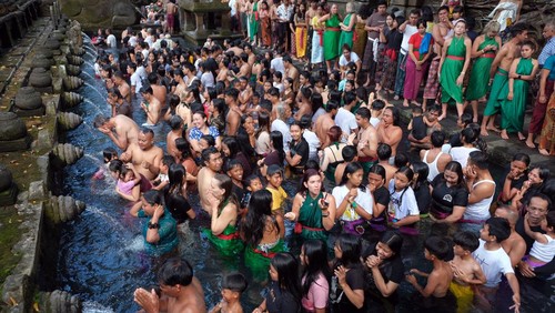 Wisatawan mancanegara berbaur dengan umat Hindu yang melakukan ritual melukat atau pembersihan diri pada hari Banyu Pinaruh di Pura Tirta Empul, Tampaksiring, Gianyar, Bali, Minggu (21/5/2023). Ritual tersebut digelar setiap enam bulan sekali yakni sehari setelah Hari Raya Saraswati oleh umat Hindu untuk menyucikan dan membersihkan diri serta pikiran secara spiritual dengan melakukan ritual pembersihan diri di laut maupun sumber mata air suci lainnya. ANTARA FOTO/Nyoman Hendra Wibowo/YU