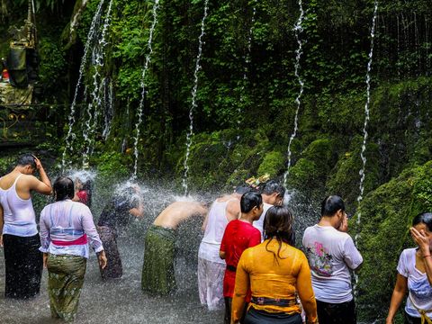 An offering is pictured as Balinese Hindus (background) perform ritual called Melukat to celebrate Banyu Pinaruh in Bebalang Village, Bangli Regency, Bali, Indonesia, on May 21, 2023. Banyu Pinaruh is a ritual for self-cleansing performed by Balinese Hindus after celebrate Saraswati Day, a day to worship a Goddess of Knowledge. Devotees bathe in the holy water of a spring, waterfall, or any other water source belived to have the apropriate cleansing power for purification. The ritual is a symbolical and literal cleansing of the body and soul aimed at preventing misfortune, sickness or havoc caused by daily activities and sins. (Photo by Garry Lotulung/NurPhoto via Getty Images)